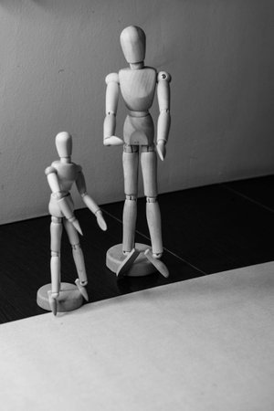 Two wooden movable mannequins of different sizes stand side by side. Shooting close-up.