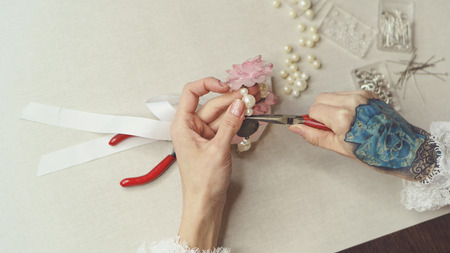 Girl fashion designer makes jewelry. Shooting close-up. She makes a ring on the decoration with pearls and artificial flowers.の写真素材
