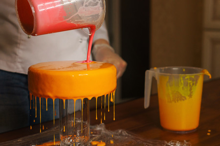 Mousse yogurt cake. The girl creates a drawing of mousse on the cake. Frozen mirror icing on the cake. Culinary masterpieces.の写真素材