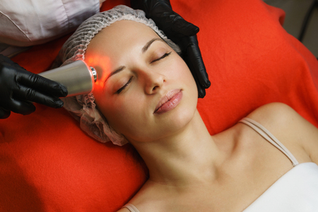 Hardware cosmetology. Beautician makes ultrasonic skin tightening client. Skin pore cleansing. Anti-aging treatments. Spa. Forehead areaの写真素材