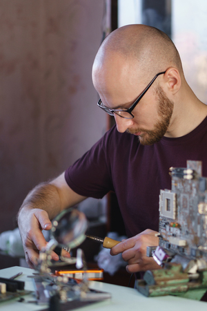 Repair motherboard. Service specialist prepares soldering iron for work. Troubleshooting.の写真素材