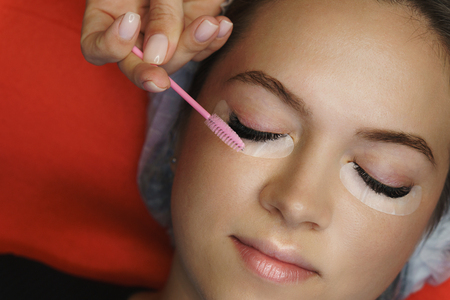 Cosmetic procedure for eyelash extensions in spa salon. Beautician makes correction of volume and...