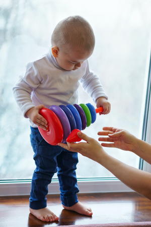 Little boy builds tower of multi-colored rings. Educational toys.の写真素材