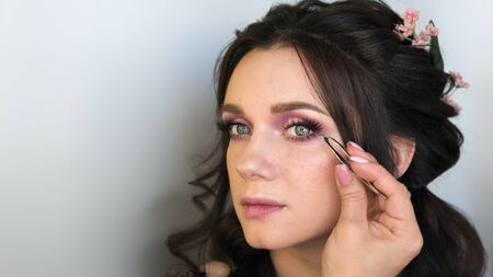 Young woman girl with perfect skin facial. Professional stylist eyelash extension and tweezers....