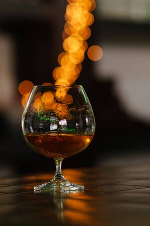 Cognac brandy in typical snifter on background of bright lights. Traditional French drink. Service and catering conceptの写真素材