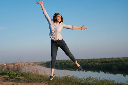 Shapely jocund girl dancing on nature background. Good-humoured lady jumping with smile.の写真素材