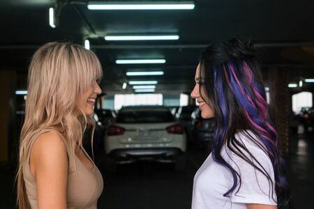 Joyful meeting of two girlfriends in underground parking. Confidential conversation, positive emotions. Female friendship conceptの写真素材
