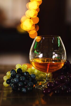 French grape brandy, strong alcoholic drink. Still life. Glass of cognac and bunch of grapes. Service and tasting concept.の写真素材