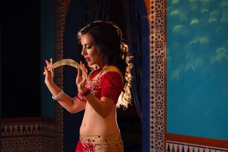 Oriental professional belly dancer in carnival shining costume with long healthy glossy hair and cane. Exotic star of bellydance. Belly Dancer During Showの写真素材