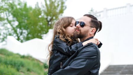 Fashionable stylish family for a walk. Daughter in the hands of dad. Happy childhood. Man's early...