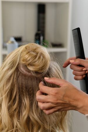 Hairtician builds upper bun. Hairstyle on bob. Hairdressing services. Creating evening hairstyles...