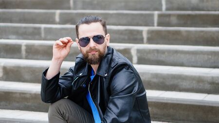 Fashion portrait of young bearded man. Handsome hipster guy posing in sunglassesの写真素材