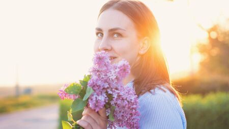 Sensuous hipster girl standing in park in evening sunshine. Stylish woman traveler in spring garden. Space for text. Atmospheric momentの写真素材