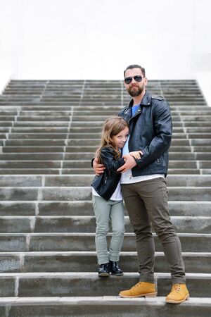 Fashionable stylish family portrait for a walk. Dad and daughter posing on the city stairs....