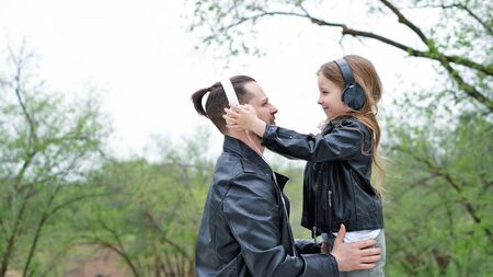 Close up portrait loving father and adorable daughter. Headphone music. Having fun together in city street. Family weekend. Fashionable stylish family for a walk. Time together. Urban casual outfit.の写真素材