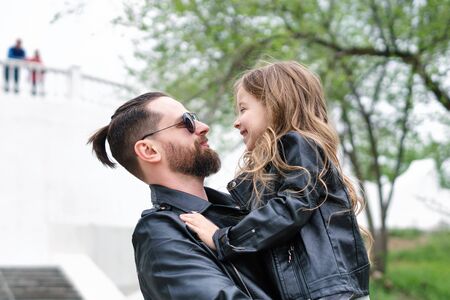 Fashionable stylish family for a walk. Daughter in the hands of dad. Happiness being a parent....