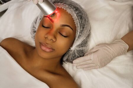 Ultrasound chromotherapy. Hardware cosmetology. Beautician carries out procedure for face skin...
