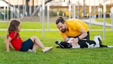 Happy family on summer walk. Dad, daughter and hunting dog have fun in park and playing together. Friendship between owner and pet. Funny expressive leisure time. Faithful friends of human.の写真素材
