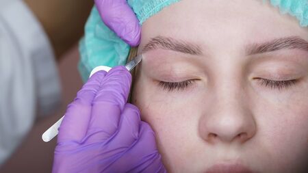 Eyebrow correction with tweezers. Final stage of creating perfect shape of eyebrows. Depilation of...