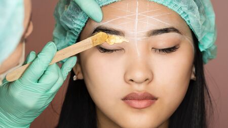 Eyebrow wax for hair removal. Cosmetic procedure. Beauty and health. Bright skin. Brow architecture in the salon of a beautician-makeup artist.の写真素材
