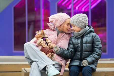 Happy family on walk with their funny terrier. Little dog with stylish hipster mom and son spend time outdoors playing and having fun. Lifestyle portrait. Love between pet and owner. Family timeの写真素材