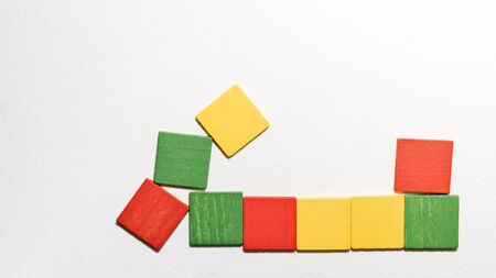 Different colorful squares wooden on white background. Geometric shapes red, green, yellow colors, top view. Concept of geometry. Copy space. Children educational logical task. Flat lay.の写真素材