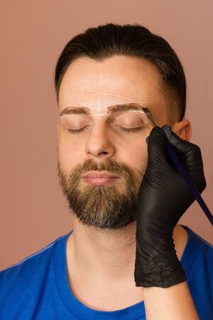 Permanent makeup for eyebrows. Tinting brows. Handsome man with eyebrows in barber shop. Brutal male...