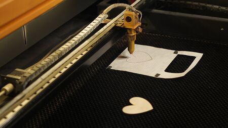 Laser cutting beam high precision on a plywood sheet. Modern technology of wood cutting. laser cut wooden 3d symbol of valentines day. Industrial laser engraving. CNC laser. Masterclass, workshopの写真素材