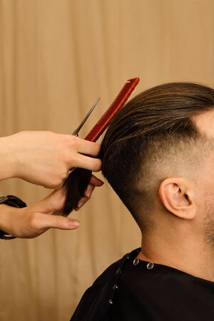 Men haircut. Fashionable hairstyle. Barber using scissors and comb. Hairdresser cutting man hair....