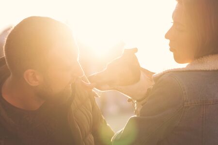 Romantic happy couple in love enjoying their time with pets. Loving couple having fun with dog at the walk. Concept people, animals and lifestyle. Sunset warmの写真素材