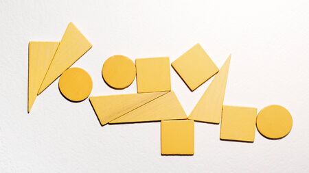 Different yellow shapes wooden on white background. Top view. Concept of geometry. Copy space. Children educational logical task. Flat lay.の写真素材