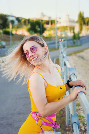 Beautiful Model in yellow dress in city street. Long Hair Blowing in the Wind. The wind fluttering...