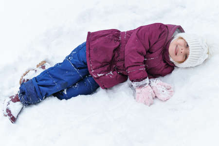 Full length portrait of a little playful girl in the snow. She has fun and leads a healthy lifestyle. Walk on a winter snowy day. Happy childhood. Games, freedom and carefreeの写真素材