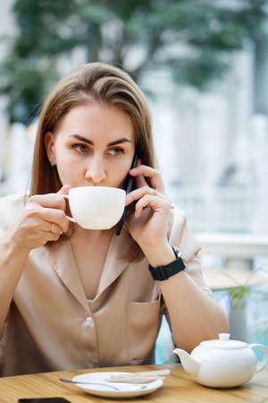 Businesswoman In Cafe Drinking Tea. Girl Listening Voice Message At Workの写真素材