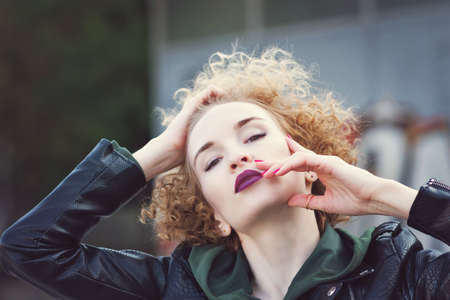 Fashionista girl with afro hairstyle with violet lips in urban. Girl wearing casual clothes posing on graffiti wall background. Casual style. Street style, lifestyle, free time conceptの写真素材