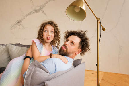 Father And Daughter Having Fun Spending Time Together At Home Making Grimaces