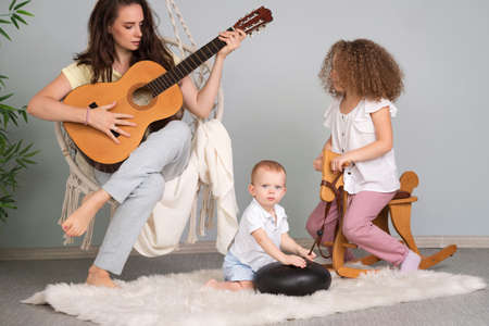 Young Mom Plays Guitar For Her Children. Spend Time Together. Family Comfortの写真素材