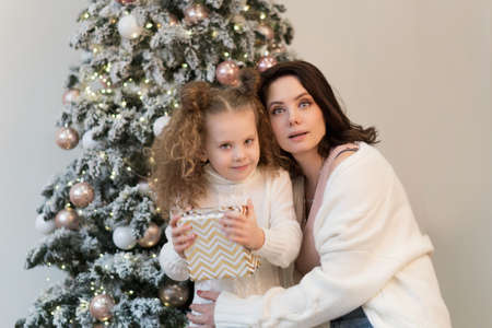 Family christmas morning. Mom and daughter open gifts. Girls greet Christmas among boxes of gifts and Christmas lights.の写真素材
