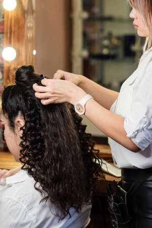 Hairdressing services. Creation of evening hairstyles fashionable stylish womens hairstyles. Hair styling process. Curls. Courses in hairdressing. Training hairdressing. Beauty industry.の写真素材
