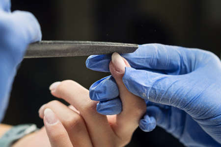 Manicurist Make Shape Nail of Client With Nail File. Professional Nail Care Service. Soft Focusの写真素材