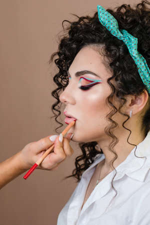Makeup artist working with model in beauty salon. Perfect skin facial. Beautiful fashion luxury makeup vivid-colour shades. Big lush beautiful lips. .Applying lip liner to client lipsの写真素材