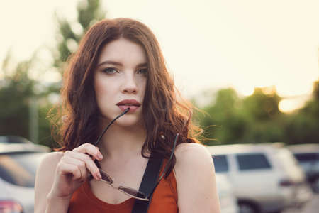 Sensual young woman an elegant haircut enjoying evening coolness in city. Portrait pretty girl...