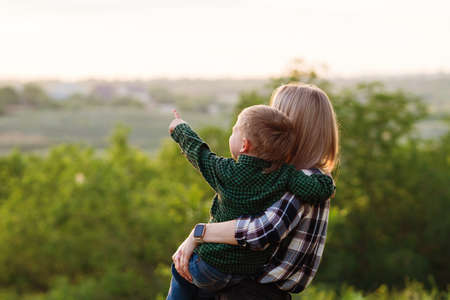 Portrait of nice young mother with pleasure spending time with precious son in Backyard. Vacation. Hugging lovely mom, having fun together, happy family enjoying lifeの写真素材
