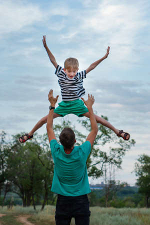 Handsome man with his little child spending time together in rural settings. Dad and son are having fun and smiling outdoorsの写真素材
