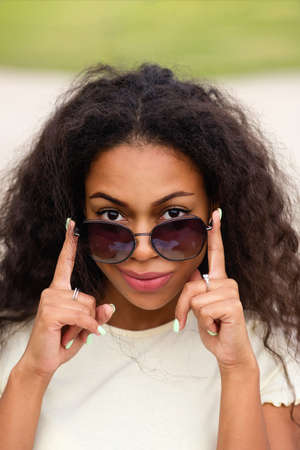 Outdoor lifestyle image of african american beautiful girl with afro loose wavy curls. Young Hipster...