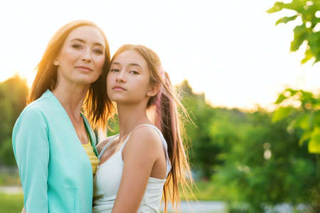 Mother with Daughter Teenager in summer setting sun. Trust relationships. Girl teen and woman. Authentic people portraitの写真素材