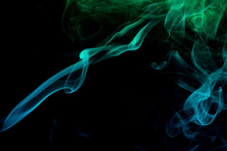 Abstract colored smoke moves on dark background. Wallpaper. Personal vaporizers fragrant steam. Concept of alternative non-nicotine smoking. E-cigarette. Texture. Design elements.の写真素材