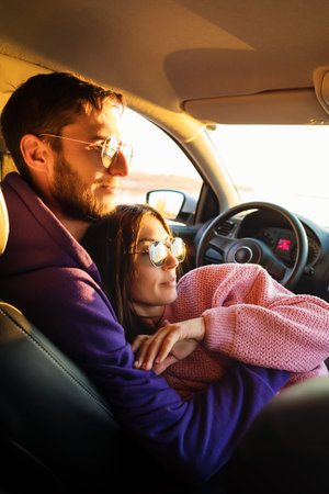 Couple Inside Car Together Admiring the Sunset. Authentic Real People Casual Style. Lifestyle Candid Portrait. Comfort Zone Warmth and Interconnectedness. Rear Seat Viewの写真素材