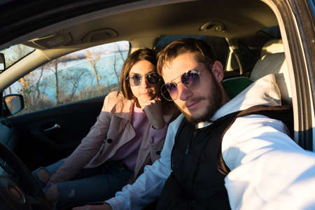 Romantic young couple taking selfie in car at sunset in countryside. Travel, road trip and...