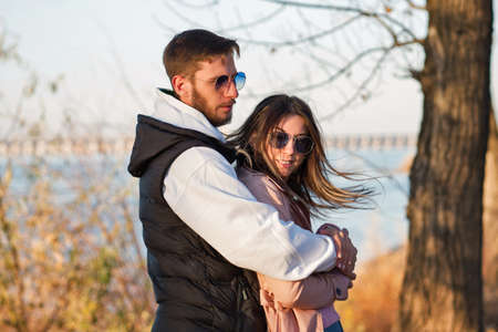 Outdoor shot young loving couple walking. Lovers posing in autumn leaves forest background. Concept of youth, love and lifestyle. Authentic real people portrait. Candid portrait.の写真素材